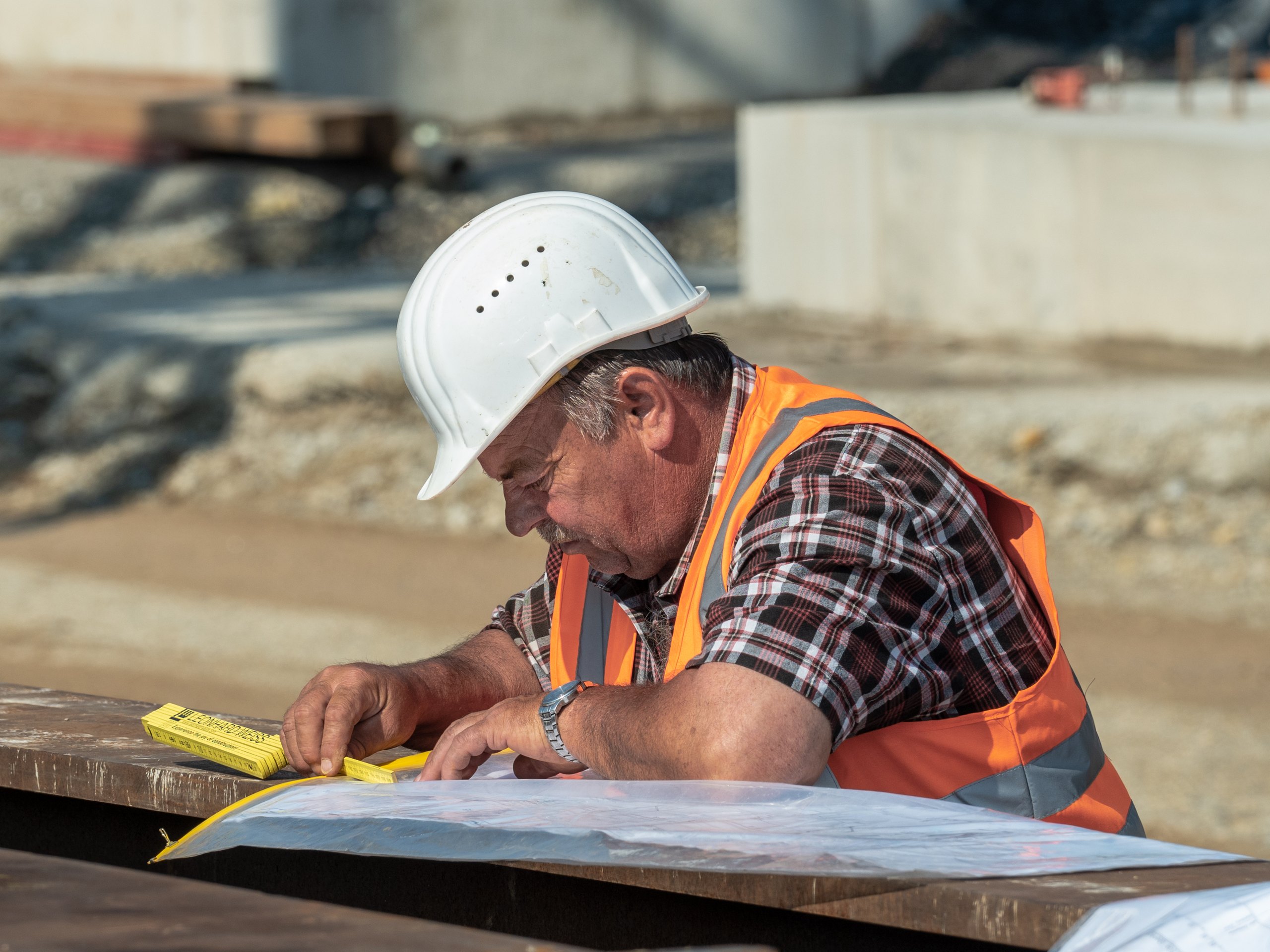 Site engineer in a hard hat reviewing construction plans
